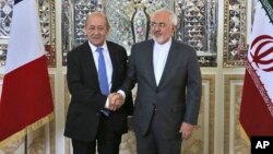 FILE - Iranian Foreign Minister Mohammad Javad Zarif, right, and his French counterpart Jean-Yves Le Drian, shake hands for journalists at the start of their meeting in Tehran, March 5, 2018. 