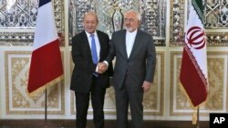 FILE - Iranian Foreign Minister Mohammad Javad Zarif, right, and his French counterpart Jean-Yves Le Drian, shake hands for journalists at the start of their meeting in Tehran, March 5, 2018. 