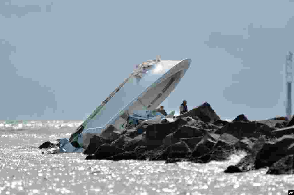 Investigators look at a boat overturned on a jetty off Miami Beach, Florida, USA.