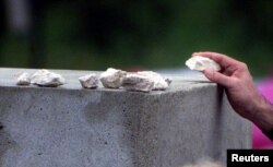 FILE - A member of the family of one of the victims places a stone on top of the monument at Jedwabne, Poland, July 10, 2001. During the German Nazi occupation of Poland, Poles killed at least 340 Jews at the site on July 10, 1941. Most of the victims were locked inside a barn that was set on fire.