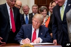 FILE - President Donald Trump signs the "Waters of the U.S." (WOTUS) executive order, Feb. 28, 2017, in the Roosevelt Room in the White House in Washington.