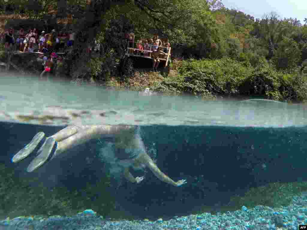 A man swims to cool off in the Blue Eye water spring and natural phenomenon occurring near the city of Sarande, Albania.
