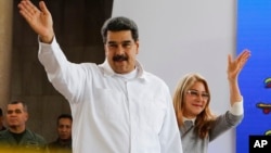 Venezuela's President Nicolas Maduro, left, and his wife Cilia Flores greet supporters upon their arrival to a meeting with Colombian citizens that reside in Venezuela, In Caracas, Venezuela, Tuesday, Sept. 25, 2018. 