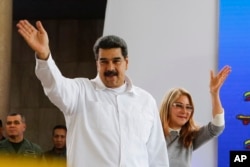 FILE - Venezuela's President Nicolas Maduro, left, and his wife Cilia Flores greet supporters upon their arrival to a meeting with Colombian citizens that reside in Venezuela, in Caracas, Sept. 25, 2018.