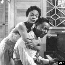 Eartha Kitt hugs Nat King Cole, playing the piano in the role of W.C. Handy, in a scene from the 1958 movie "St. Louis Blues."