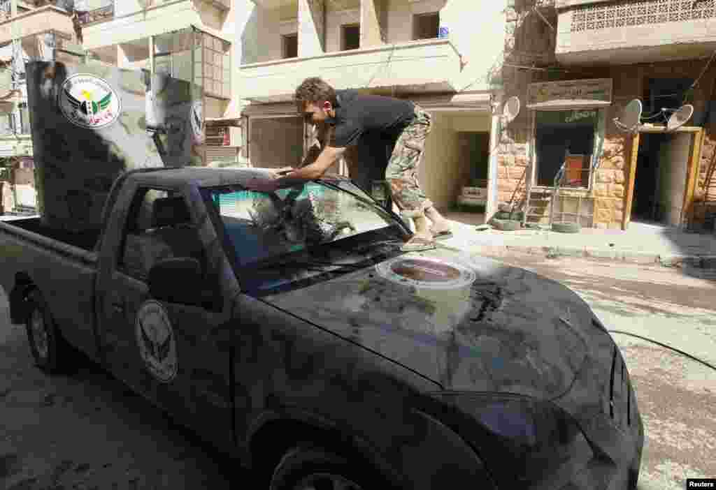 A member of "Free Men of Syria" brigade, operating under the Free Syrian Army, washes a vehicle in Aleppo's Bustan al-Qasr, Sept. 9, 2013.