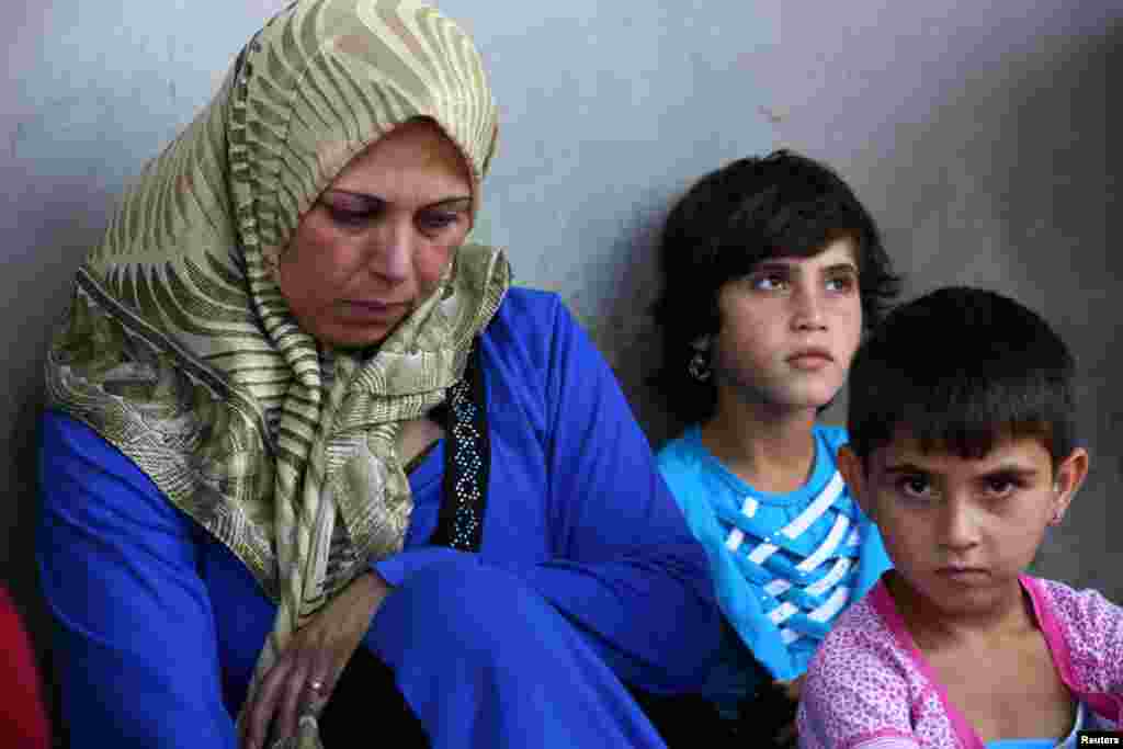 A Syrian refugee sits with her daughters where they are staying temporarily with their relatives in Wadi Khaled town, Lebanon, July 24, 2012. 