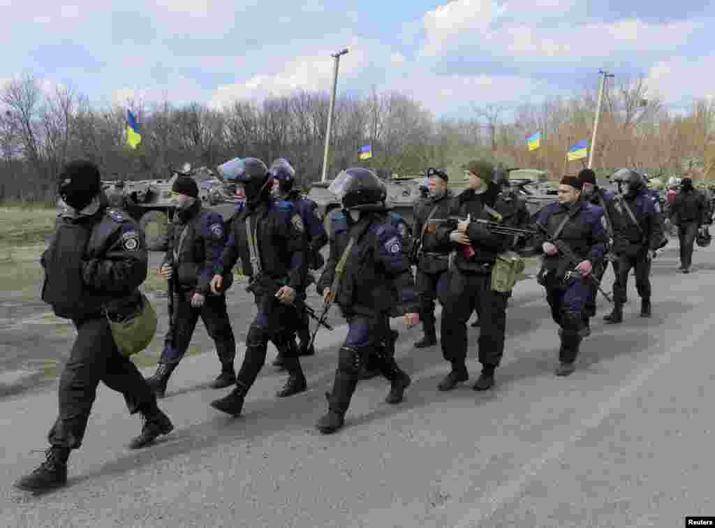 Members of the Ukrainian Interior Ministry walk past armored personnel carriers at a checkpoint near the town of Izium, eastern Ukraine, April 15, 2014.