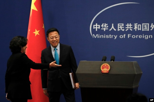 中国外交部发言人华春莹引导新任发言人赵立坚走入例行记者会会场。（2020年2月24日）