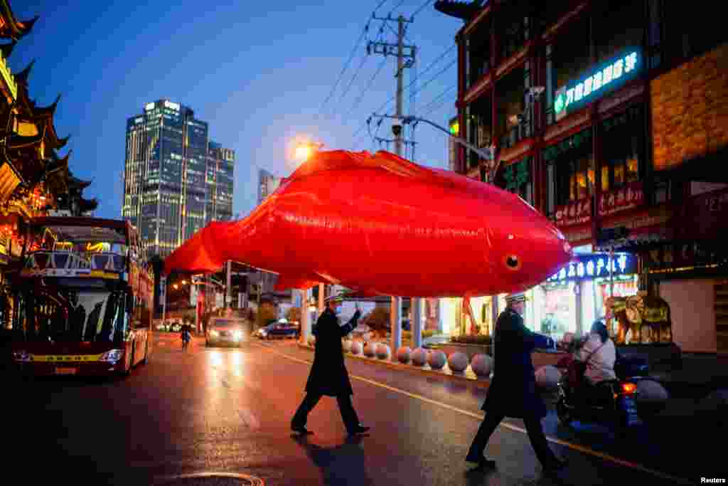 Security guards wearing face masks carry a giant balloon in the shape of a fish ahead of the Chinese Lunar New Year festivity at Yu Garden, following the coronavirus outbreak in Shanghai, China.