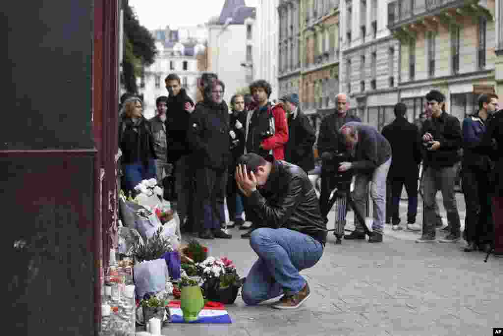 A man holds his head in his hands as he lays flowers in front of the Carillon cafe, in Paris, Nov. 14, 2015.