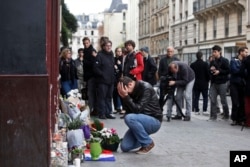 FILE - A man holds his head in his hands as he lays flowers in front of the Carillon cafe, in Paris, Nov. 14, 2015.
