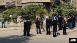 Des policiers et des résidents locaux se tiennent devant un bâtiment où une explosion a eu lieu dans la banlieue sud de Maadi, dans la capitale égyptienne, le Caire, le 24 mars 217. 
