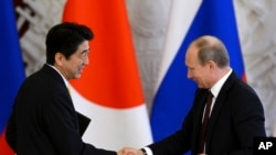 Prezida w'Uburusiya, Vladimir Putin (R) ariko aramukanya n'umushikiranganji wa mbere w'Ubuyapani,Shinzo Abe mu rugendo rwiwe i Moscou, kw'italiki 29 z'ukwezi kwa kane, 2013.