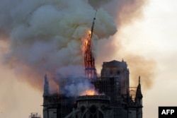 The steeple and spire of the landmark Notre Dame Cathedral collapses as the cathedral is engulfed in flames in central Paris, April 15, 2019.