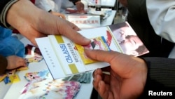 FILE - A Chinese volunteer hands free condom and AIDS prevention brochures during an HIV/AIDS awareness campaign in Beijing.