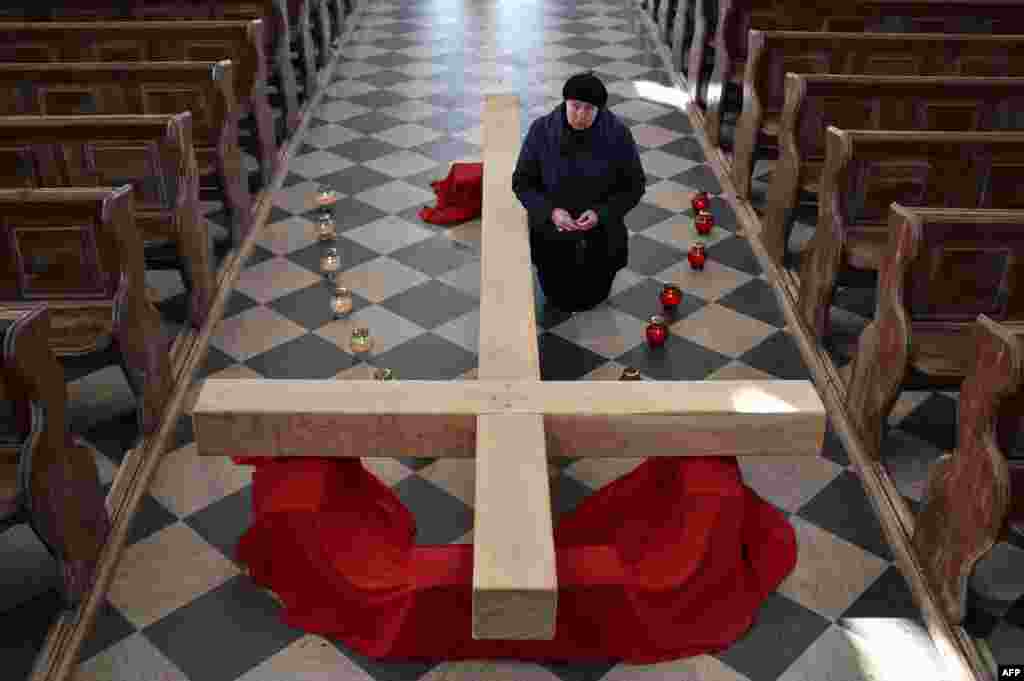 A Catholic Christian believer kneels next to a giant cross during the Sunday service in the town of Achmiany, some 130 km northwest of Minsk, during Palm Sunday celebrations which mark a week before Easter.