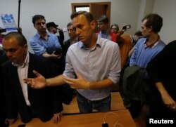 Russian opposition leader Alexei Navalny talks to journalists after he was sentenced by a court to 20 days in jail on charges of repeatedly violating laws governing the organization of public meetings and rallies, during a hearing in Moscow, Russia, Oct.