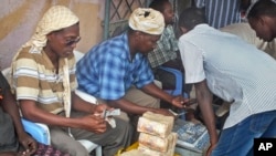 FILE - A customer of Dahabshiil, a Somali remittance company, exchanges U.S. dollars for Somali shillings outside the company's headquarters in Mogadishu, Somalia.