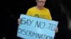 FILE - An albino holds a placard during an Albinism awareness campaign in Harare, Zimbabwe, June 18, 2016. 