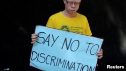 FILE - An albino holds a placard during an Albinism awareness campaign in Harare, Zimbabwe, June 18, 2016. 