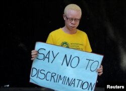 FILE - An albino holds a placard during an Albinism awareness campaign in Harare, Zimbabwe, June 18, 2016.