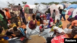 FILE - Internally displaced Somali people gather around a water point at a settlement camp in Hodan district south of capital Mogadishu, Somalia.