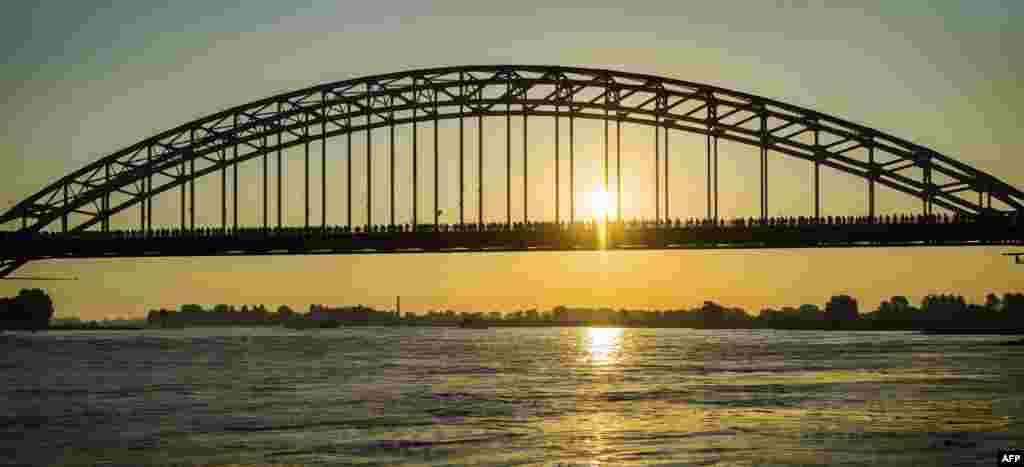 Participants cross a bridge over the Waal river during the first day of the 100th edition of the annual four days march of Nijmegen, the Netherlands.