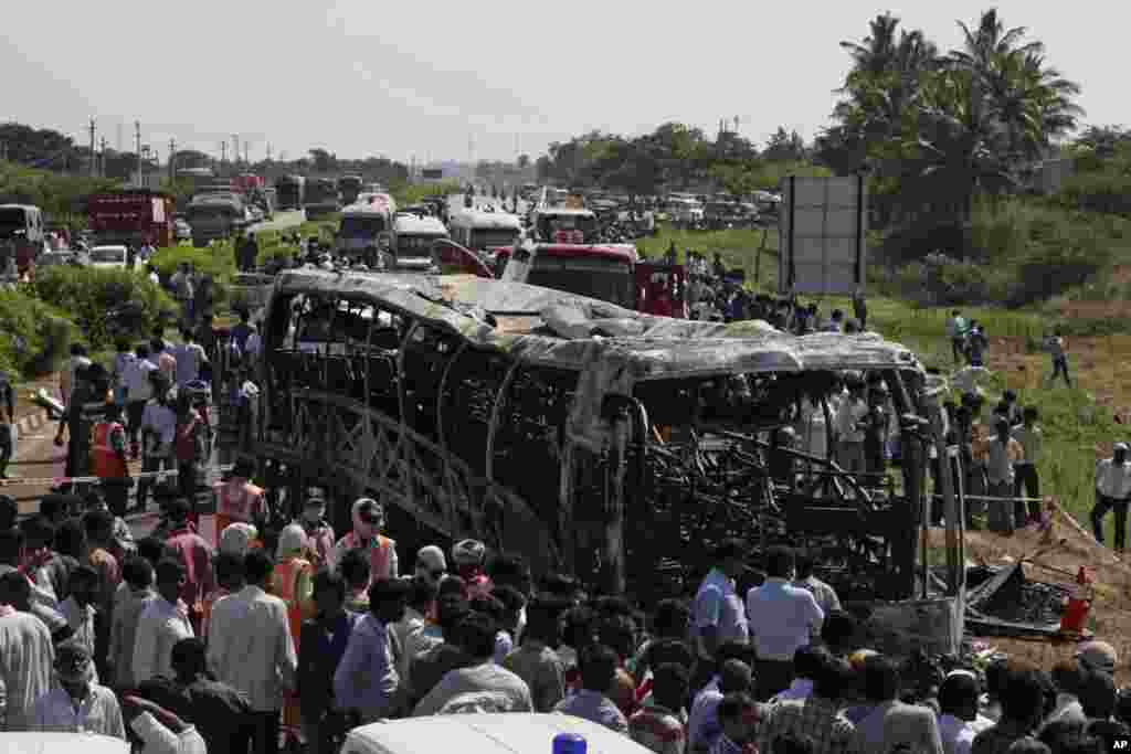 Rescuers and others gather after a bus crashed into a highway barrier and erupted in flames, Mehabubnagar, Andhra Pradesh, India, Oct. 30, 2013. 