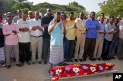 FILE - Mourners pray over the body of Somali journalist Mohamed Ibrahim, a news presenter for Kalsan TV, before his burial in Mogadishu, Somalia, Dec. 12, 2017.