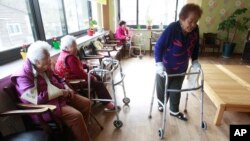 FILE - Kim Gun-ja, 89, right, former comfort woman who was forced to serve for the Japanese troops as a sexual slave during World War II, passes by other comfort woman Yi Ok-seon, 88, left, and Kim Wei-han, 86, at the House of Sharing, a nursing home.