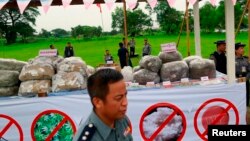FILE - Police officers are seen near seized drugs which will be burnt, at an event to mark International Day against Drug Abuse and Illicit Trafficking outside Rangoon.