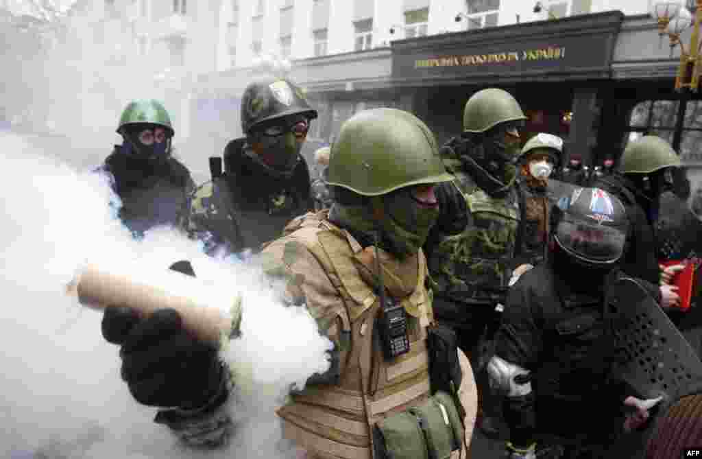 A man holds a smoke bomb as anti-government protesters take part in a protest rally in front of the Prosecutor General building in Kyiv, Ukraine. Protesters armed with shields and clubs demanded the government stop prosecuting cases against anti-government activists involved in clashes with police.