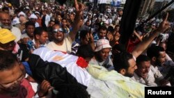 Patizan prezidan dechouke Ejip la, Mohamed Morsi, ap pote kadav yon kòlèg manifestan yo ki te tonbe anba bal tou pre katye jeneral Gad Repiblikèn nan nan vil Lekèr (8 jiyè 2013).