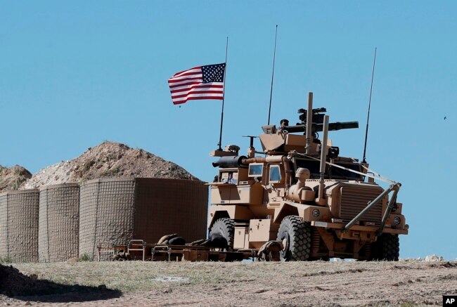 FILE - A U.S. soldier sits atop an armored vehicle at a newly installed position, near the tense frontline between the U.S-backed Syrian Manbij Military Council and Turkey-backed fighters, in Manbij, northern Syria, April 4, 2018.