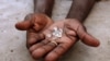 FILE - An illegal diamond dealer from Zimbabwe displays diamonds for sale in Manica, Mozambique near the border with Zimbabwe on September 19, 2010. 