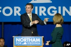 FILE - Virginia Democrat Ralph Northam points to his wife, Pam, as they celebrate his election victory with supporters at George Mason University in Fairfax, Va., Nov. 7, 2017.