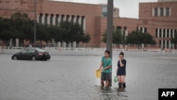 Grant Lu (L) and Naomi Pringle stand in a flooded parking lot on the campus of Rice University afer it was inundated with water from Hurricane Harvey on Aug. 27, 2017 in Houston, Texas. 