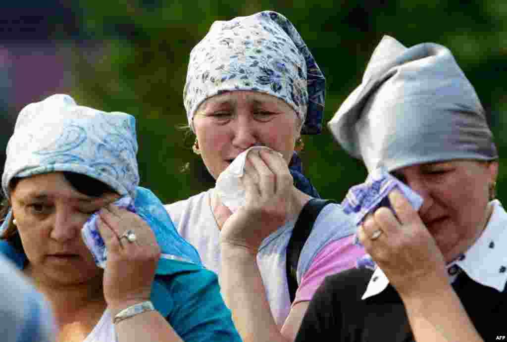 July 12: Relatives of Faina Valiullina, a victim of cruise ship sinking, cry during her funeral outside Kazan, Russia. Russia is observing a day of mourning for victims of a cruise vessel that sank on Sunday. Divers work deep underwater in a Volga River r