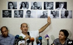 FILE - Egyptian lawyer and former presidential candidate Khaled Ali points to photos of jailed activists, who were arrested during protests over two disputed Red Sea islands, including Egyptian rights lawyer Malek Adly, top row third right, during a press conference, in Cairo, Egypt, June 22, 2016. In the following month, an Egyptian court ordered the release of the prominent rights lawyer held in solitary confinement for three months after he challenged in court a decision by the country's president to hand over two Red Sea islands to Saudi Arabia.