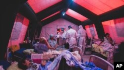 FILE - Medical staff treat a coronavirus patient at a tent hospital erected for COVID-19 patients in Kakhovka, Ukraine, Nov. 7, 2021.