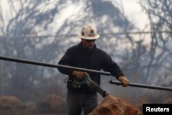 A Pacific Gas & Electric lineman cuts a downed power line during the Camp Fire in Paradise, California, Nov. 8, 2018.