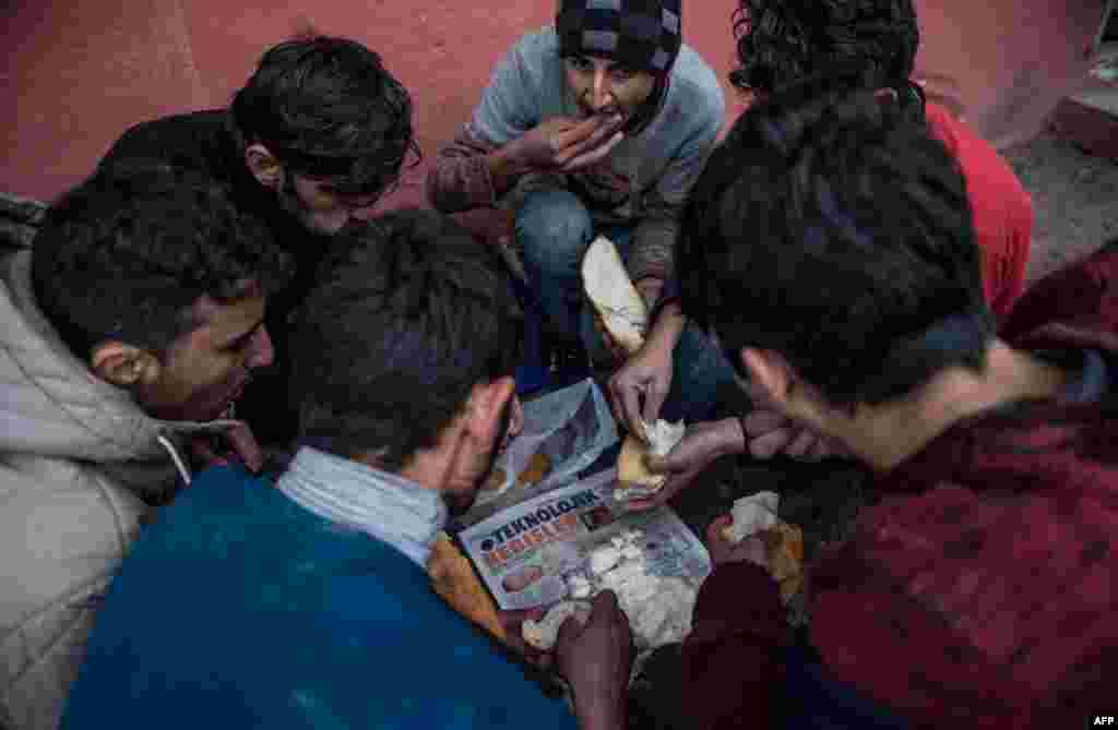 Afghan refugees in Turkey eat food provided by villagers in Edirne December 9, after having been deported by Greece.