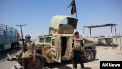 Các chiến binh Nhà nước Hồi giáo đứng cạnh một chiếc Humvee chiếm được bên ngoài trạm kiểm soát của máy lọc dầu Beiji, khoảng 250 km (155 dặm) phía bắc Baghdad, Iraq. (Ảnh chụp ngày 19/6/2014).