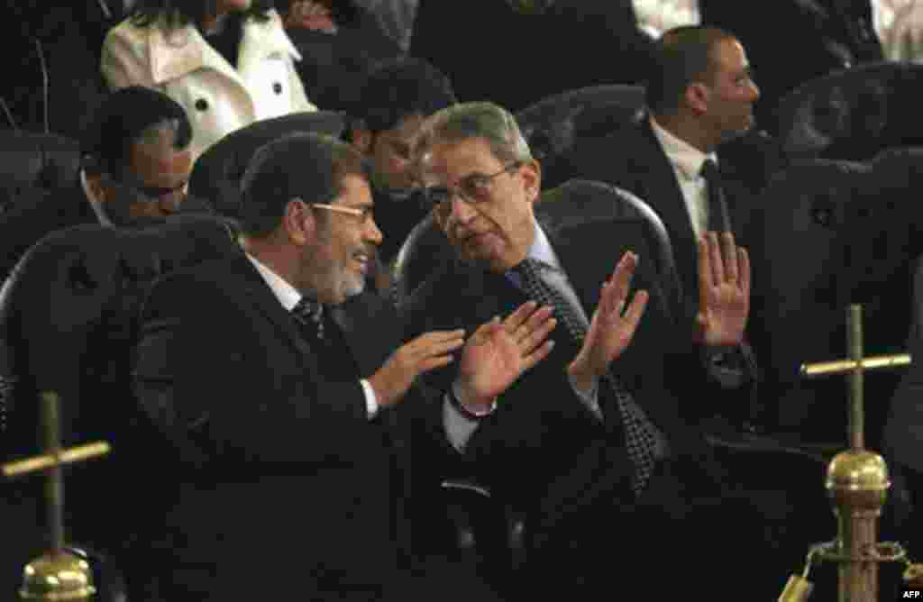 Mohamed Morsi, left, of Egypt's Muslim Brotherhood and Egyptian presidential hopeful Amr Moussa, right, talk before Christmas Eve mass, led by Coptic Pope Shenouda III at the Coptic cathedral in Cairo, Egypt, Friday, Jan. 6, 2012. This is the first Christ