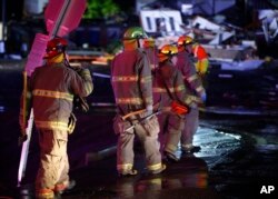 Firefighters walk to an area of debris from a hotel and a mobile home park in El Reno, Okla., Sunday, May 26, 2019, following a likely tornado touchdown late Saturday night.