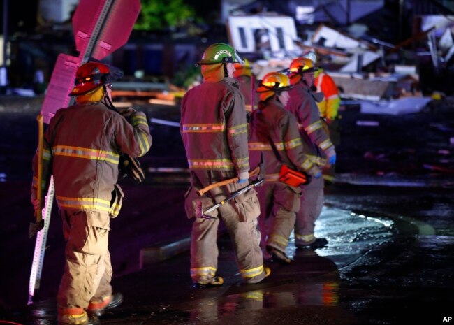Firefighters walk to an area of debris from a hotel and a mobile home park in El Reno, Okla., Sunday, May 26, 2019, following a likely tornado touchdown late Saturday night.