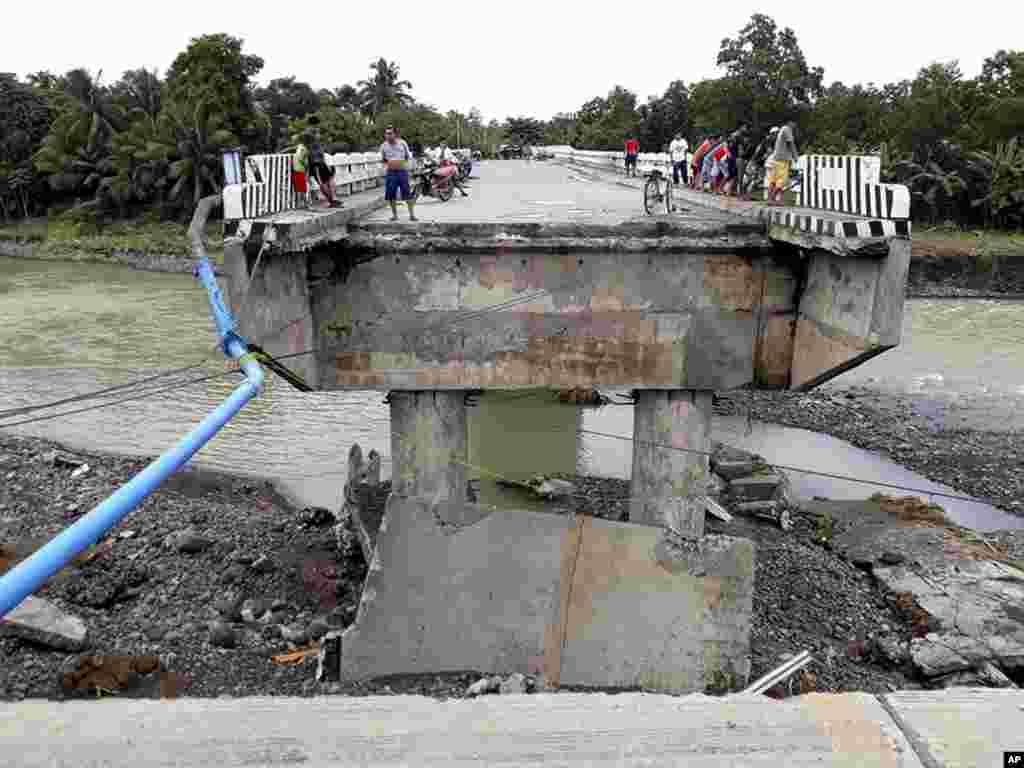 People gather on a bridge that was damaged by the flooding brought about by tropical storm Tembin in Zamboanga Del Sur in southern Philippines. Tropical Storm Tembin unleashed flash floods that swept away people and houses and set off landslides in the southern Philippines.