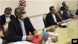 This combined photo released by the Iranian Foreign Ministry, shows Iranian diplomats attending a virtual talk on nuclear deal with representatives of world powers, in Tehran, Iran, Friday, April 2, 2021. The chair of the group including the European Unio