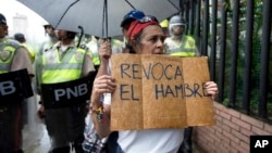  woman holds a sign with a message that in reads in Spanish; "Revoke hunger" during a protest march in Caracas, Venezuela, Wednesday, July 27, 2016. 